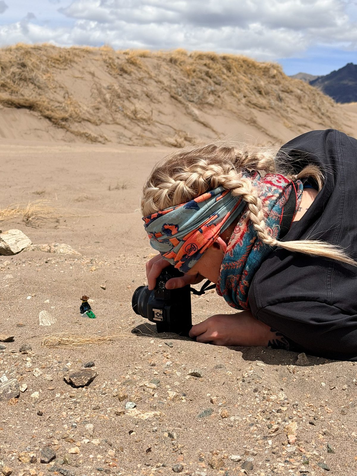 Bri crouched down photographing a minifig in the sand dunes
