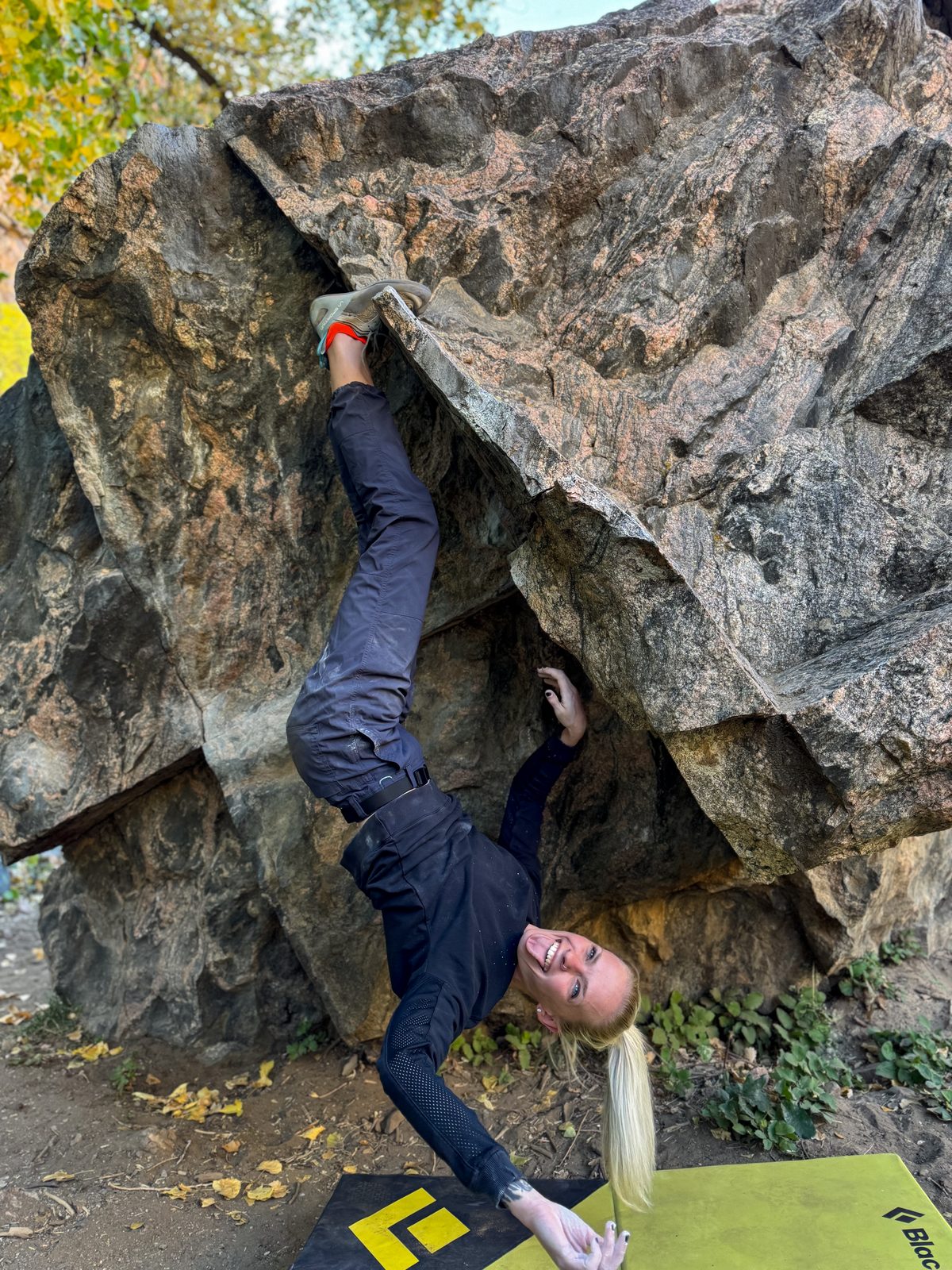 Bri bouldering, hanging upside down on a rock formation